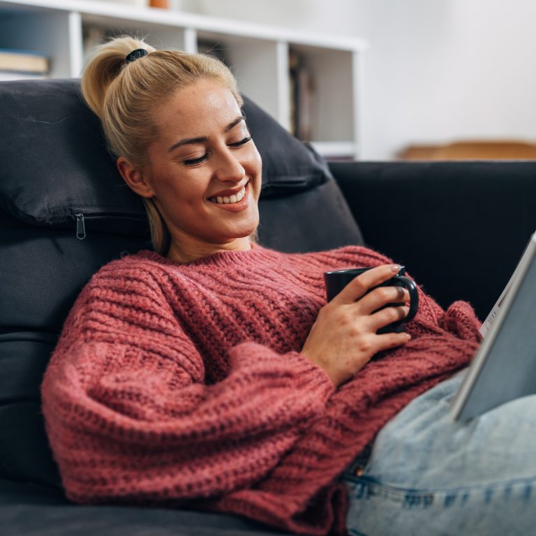 Person reclining on a sofa using a smartphone in a modern living space.